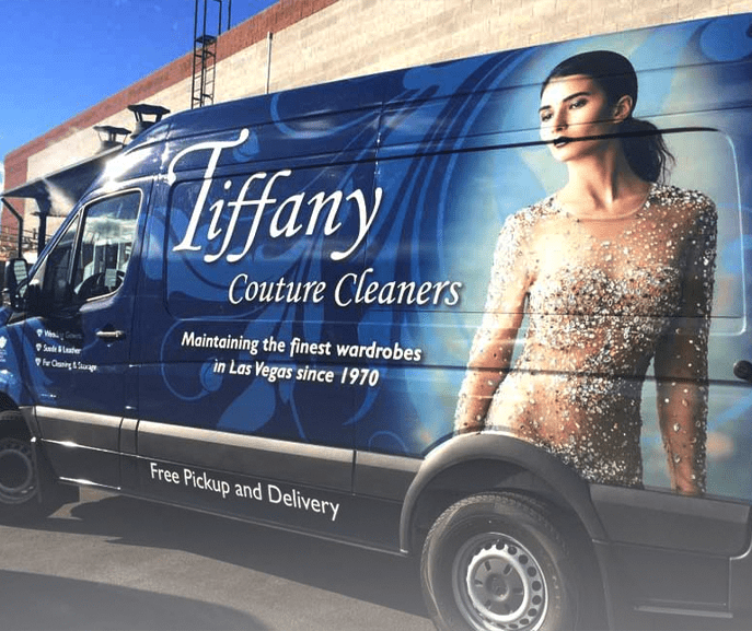 A blue Tiffany Couture Cleaners van features a large image of a woman in a jeweled dress and advertises wardrobe cleaning services in Las Vegas with free pickup and delivery.