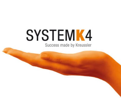 An orange-tinted hand is held out flat beneath the words "SYSTEM K4 Success made by Kreussler" on a white background.